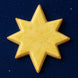 3.5 inch Star of Bethlehem Moravian Star Metal Cookie Cutter shaped yellow cookie on a dark starry background.