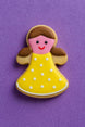 Decorative cookie shaped like a girl with a yellow dress on a purple background from a 2 inch Mini Gingerbread Girl Metal Cookie Cutter