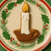4 inch Candle Metal Cookie Cutter shaped cookie on a festive plate with holly and pine decoration.