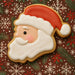 4 inch Santa Face Metal Cookie Cutter shaped cookie decorated with red and white icing on festive background.