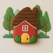 3 inch Folk Gingerbread House Metal Cookie Cutter shaped cookie with colorful frosting surrounded by green trees.