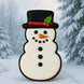 Decorative snowman cookie with a black top hat and red ribbon against a snowy background from a 5 inch Snowman Metal Cookie Cutter