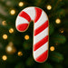3.5 inch Candy Cane Metal Cookie Cutter displayed with colorful icing on a festive background of Christmas lights.
