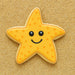 Star-shaped cookie with a smiley face on a sandy background from a 3.25 inch Folk Star or Starfish Metal Cookie Cutter