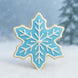3 inch Snowflake Metal Cookie Cutter shaped cookie decorated in blue icing with white details, set against a snowy background.