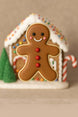 Gingerbread man cookie with a small gingerbread house and candy canes on a beige background from a 3 inch Gingerbread Boy Metal Cookie Cutter