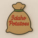 Decorative cookie shaped like a bag of Idaho Potatoes on a beige background from a 3.5 inch Santa Potato Money Sack Metal Cookie Cutter