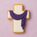 Decorative cookie shaped like a cross with a purple scarf on a pink background from a 2.75 inch Cross Metal Cookie Cutter
