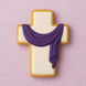 Decorative cookie shaped like a cross with a purple scarf on a pink background from a 2.75 inch Cross Metal Cookie Cutter