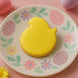 Yellow chick-shaped cookie on a decorative plate with Easter designs on a pink background from a 3 inch Easter Baby Chick Metal Cookie Cutter