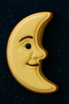 3 inch Man in the Moon Metal Cookie Cutter shaped cookie with yellow icing and a smiling face on a dark background.