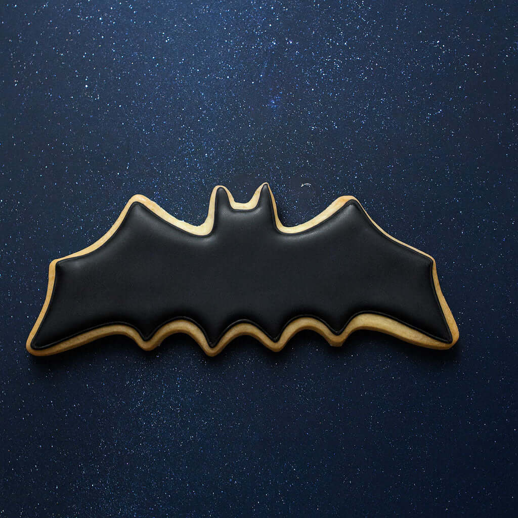 4 inch Flying Bat Metal Cookie Cutter shaped bat cookie decorated in black icing on a starry background.