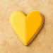 Heart-shaped cookie with yellow icing on a beige background from a 2 inch Heart Metal Cookie Cutter