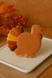 4 inch Turkey Metal Cookie Cutter shaped turkey cookie decorated in autumn colors on a white plate.