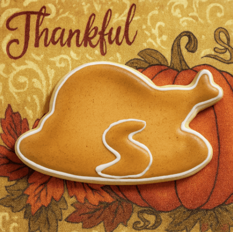 4.5 inch Thanksgiving Turkey Dinner Metal Cookie Cutter shaped cookie on a festive Thanksgiving background.