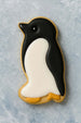 Penguin-shaped cookie with black and white icing on a textured gray background from a 3 inch Penguin Metal Cookie Cutter