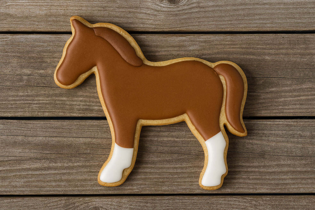 4 inch Horse Metal Cookie Cutter shaped cookie decorated with brown icing and white hooves on wooden background.