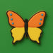 Butterfly-shaped cookie with orange and yellow wings on a green background from a 3 inch Butterfly Metal Cookie Cutter