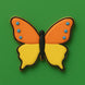 Butterfly-shaped cookie with orange and yellow wings on a green background from a 3 inch Butterfly Metal Cookie Cutter