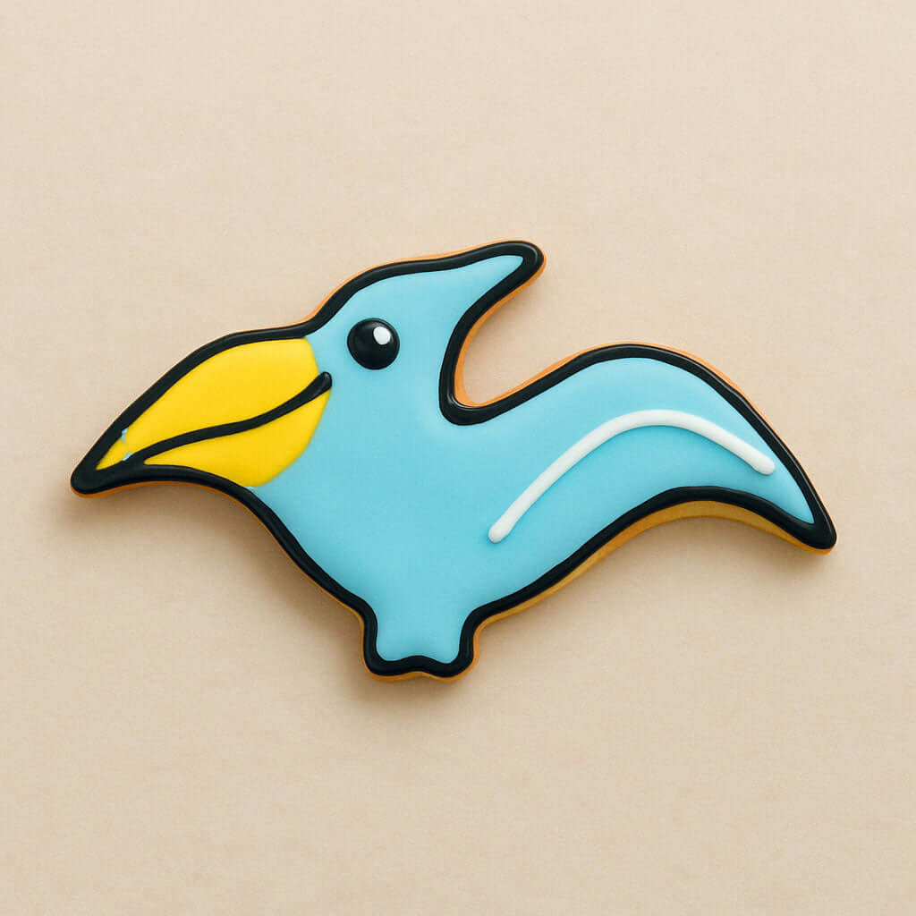 Cookie shaped like a blue pterodactyl  with a yellow beak on a beige background from a 4.75 inch Pterodactyl Metal Cookie Cutter