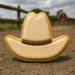 Cowboy hat-shaped cookie on a dirt ground with a blurred barn and fence in the background from a 4 inch Cowboy Hat Metal Cookie Cutter