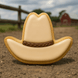 Cowboy hat-shaped cookie on a dirt ground with a blurred barn and fence in the background from a 4 inch Cowboy Hat Metal Cookie Cutter
