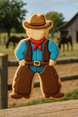 Decorative cookie shaped like a cowboy with a background of a barn and horses from a 4.25 inch Cowboy Metal Cookie Cutter