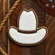 Cookie shaped like a cowboy hat on a wooden background with rope and leather from a 2.75 inch Cowboy Hat Metal Cookie Cutter