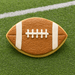 Football-shaped cookie on a green field background from a 3.5 inch Football Metal Cookie Cutter
