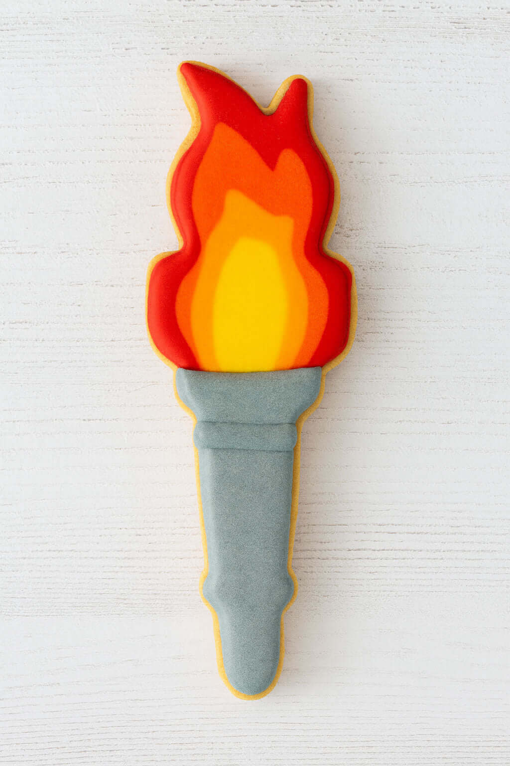 Decorative cookie shaped like a torch with flames on a white background from a 5 inch Torch Metal Cookie Cutter