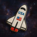 Space shuttle cookie with 'USA' and American flag on a space-themed background from a 4.5 inch Space Shuttle Metal Cookie Cutter