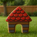Dog house-shaped cookie with red roof and brown body on grass from a 3.5 inch Dog House Metal Cookie Cutter