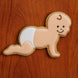 Cookie shaped like a crawling baby with a face on a wooden surface from a 5 inch Crawling Baby Metal Cookie Cutter