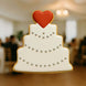 4.25 inch Wedding Cake Metal Cookie Cutter shaped cookie decorated with pearls and a red heart on top.
