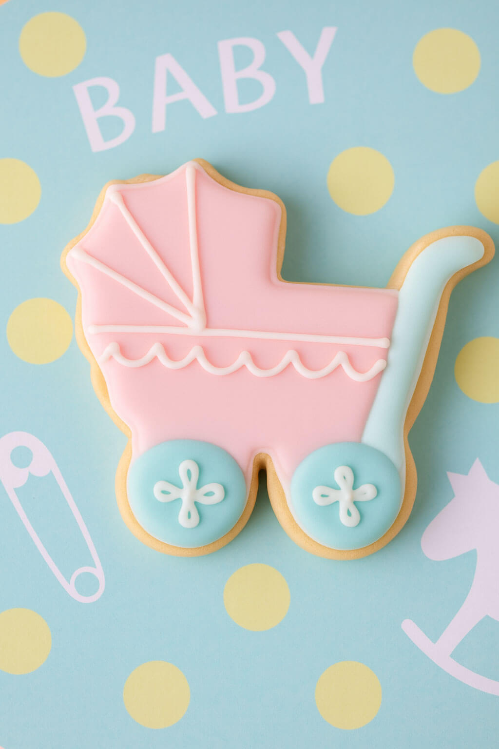 Cookie shaped like a baby stroller on a blue background with polka dots and 'BABY' text from a 4 inch Baby Carriage Metal Cookie Cutter