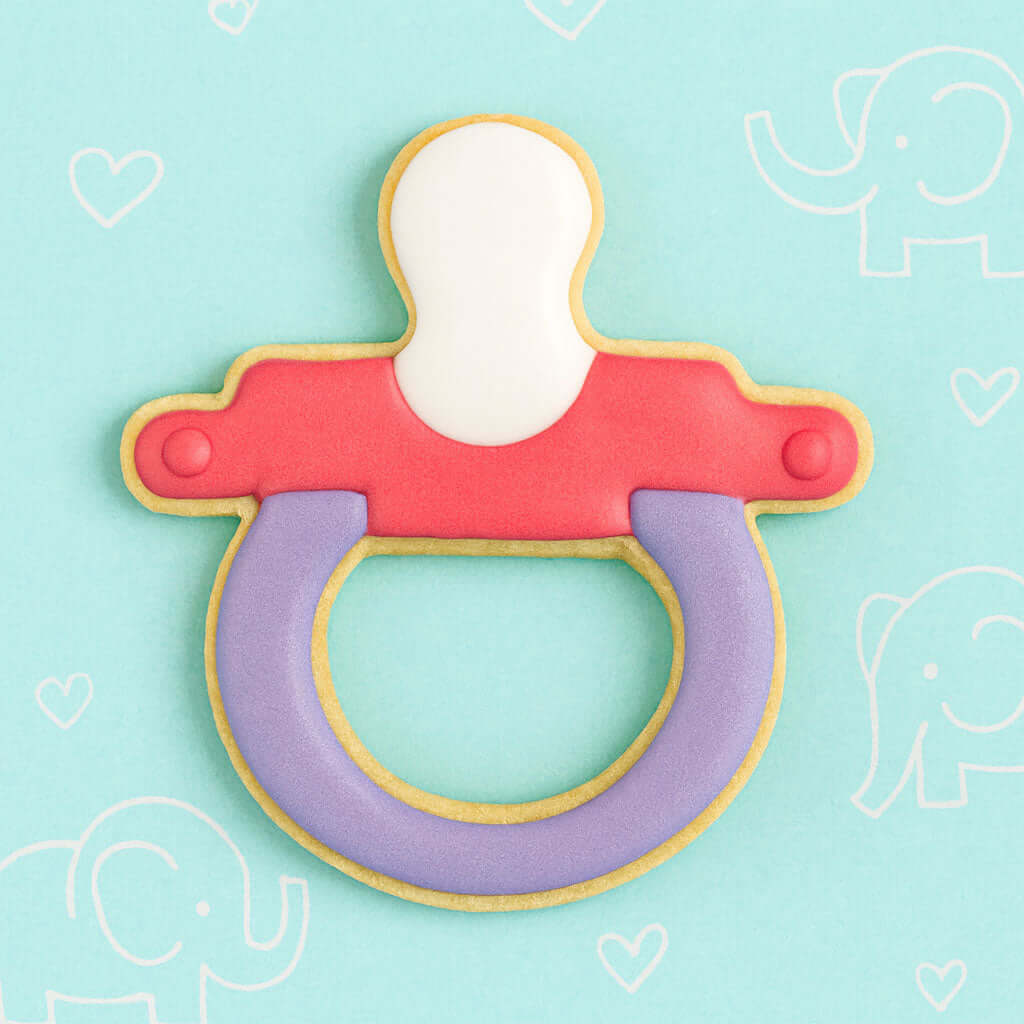 Cookie-shaped pacifier on a light blue background with heart and elephant designs from a 3 inch Baby Pacifier Metal Cookie Cutter