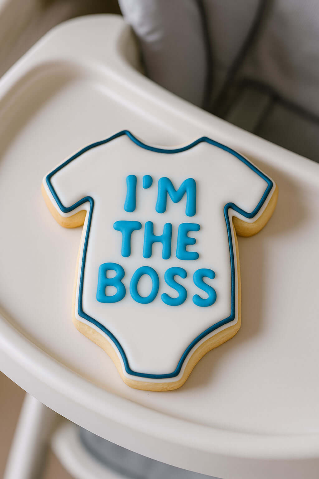 Cookie shaped like a baby onesie with 'I'm the Boss' text on a white tray from a 3.5 inch Baby One Piece T Shirt Metal Cookie Cutter