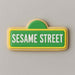 Cookie shaped like a Sesame Street sign with green background and white text on a gray background from a 5 inch Street Sign Metal Cookie Cutter