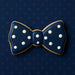5 inch Bow Tie Metal Cookie Cutter shaped cookie decorated with white dots on dark blue background.
