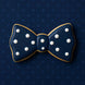 5 inch Bow Tie Metal Cookie Cutter shaped cookie decorated with white dots on dark blue background.