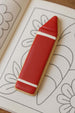 5 inch Crayon Pencil Metal Cookie Cutter shaped cookie resting on a coloring book page.