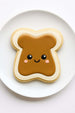 Cookie shaped like a piece of toast with peanut butter, on a white plate from a 4.75 inch Toast Metal Cookie Cutter