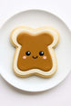 Cookie shaped like a piece of toast with peanut butter, on a white plate from a 4.75 inch Toast Metal Cookie Cutter