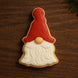 Cookie shaped like a gnome with a red hat and white beard on a wooden surface from a 5 inch Gnome Metal Cookie Cutter