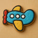 Decorative cookie shaped like a airplane with blue body, yellow wings, and red propeller on a beige background from our 4 inch Airplane Metal Cookie Cutter