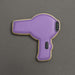Cookie shaped like a purple hair dryer on a gray background from a 4 inch Hair Dryer Metal Cookie Cutter