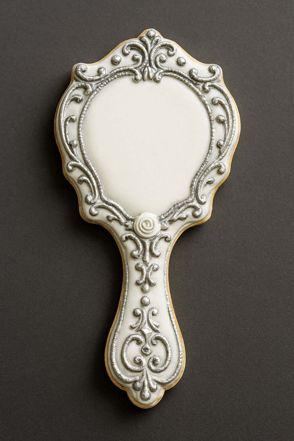 Decorative cookie shaped like a hand mirror on a dark background from a 4.5 inch Hand Mirror Metal Cookie Cutter
