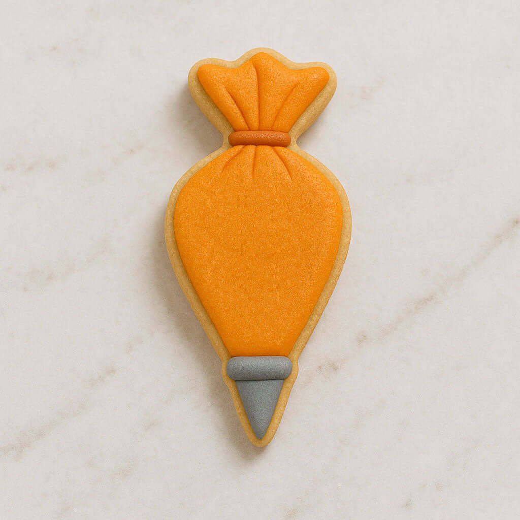 Piping bag cookie with orange body and gray base on a light marble background from a 4 inch Piping Bag Metal Cookie Cutter