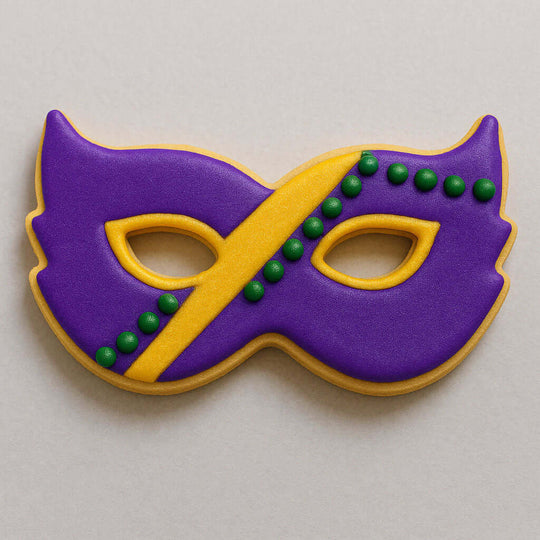 Cookie decorated like a Mardi Gras mask with purple, yellow, and green icing on a light gray background from a 4 inch Mardi Gras Mask Metal Cookie Cutter