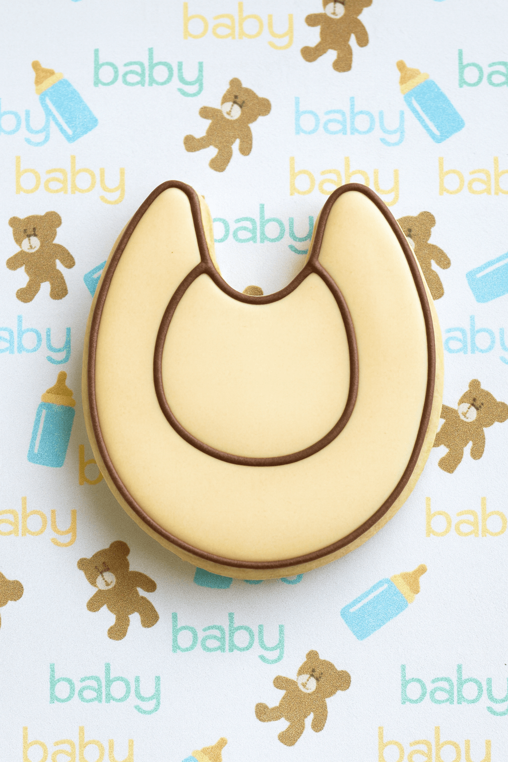Baby bib cookie on a background with baby-themed illustrations from a 3.25 inch Baby Bib Metal Cookie Cutter